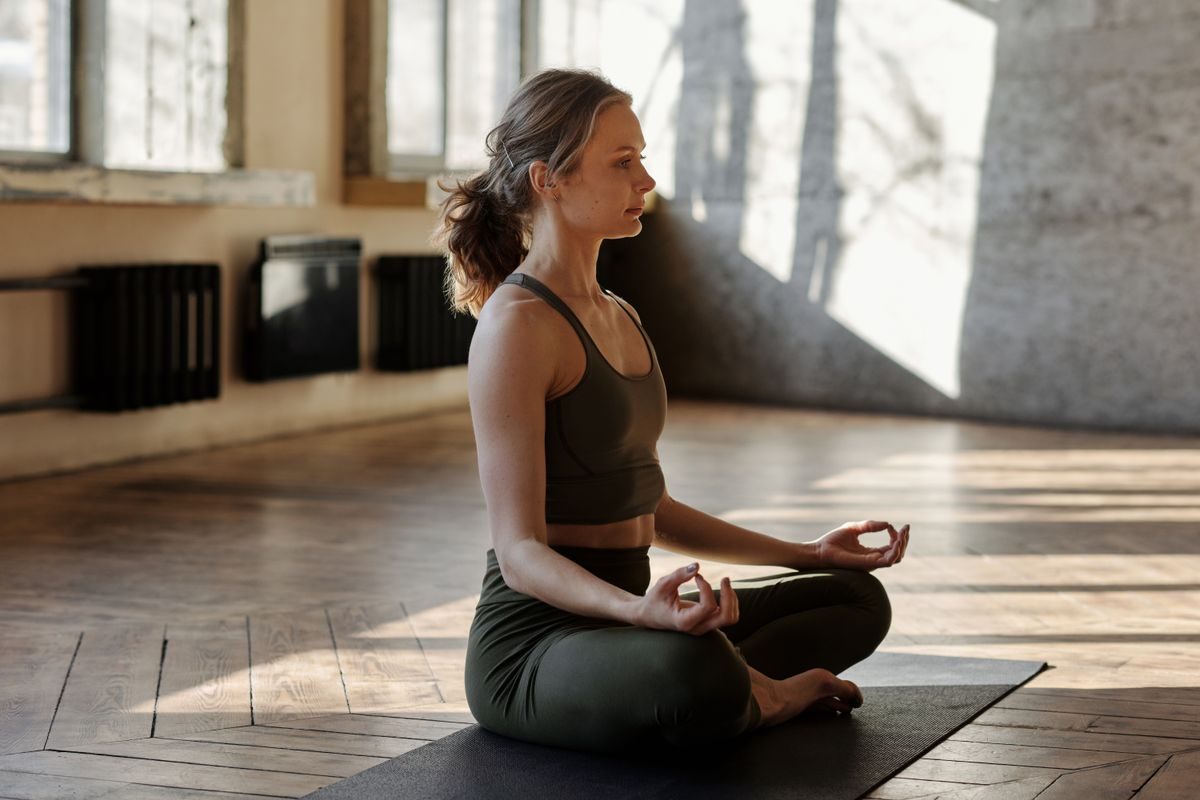 A woman sitting calmly in meditation in morning light — homeopathy for stress and anxiety